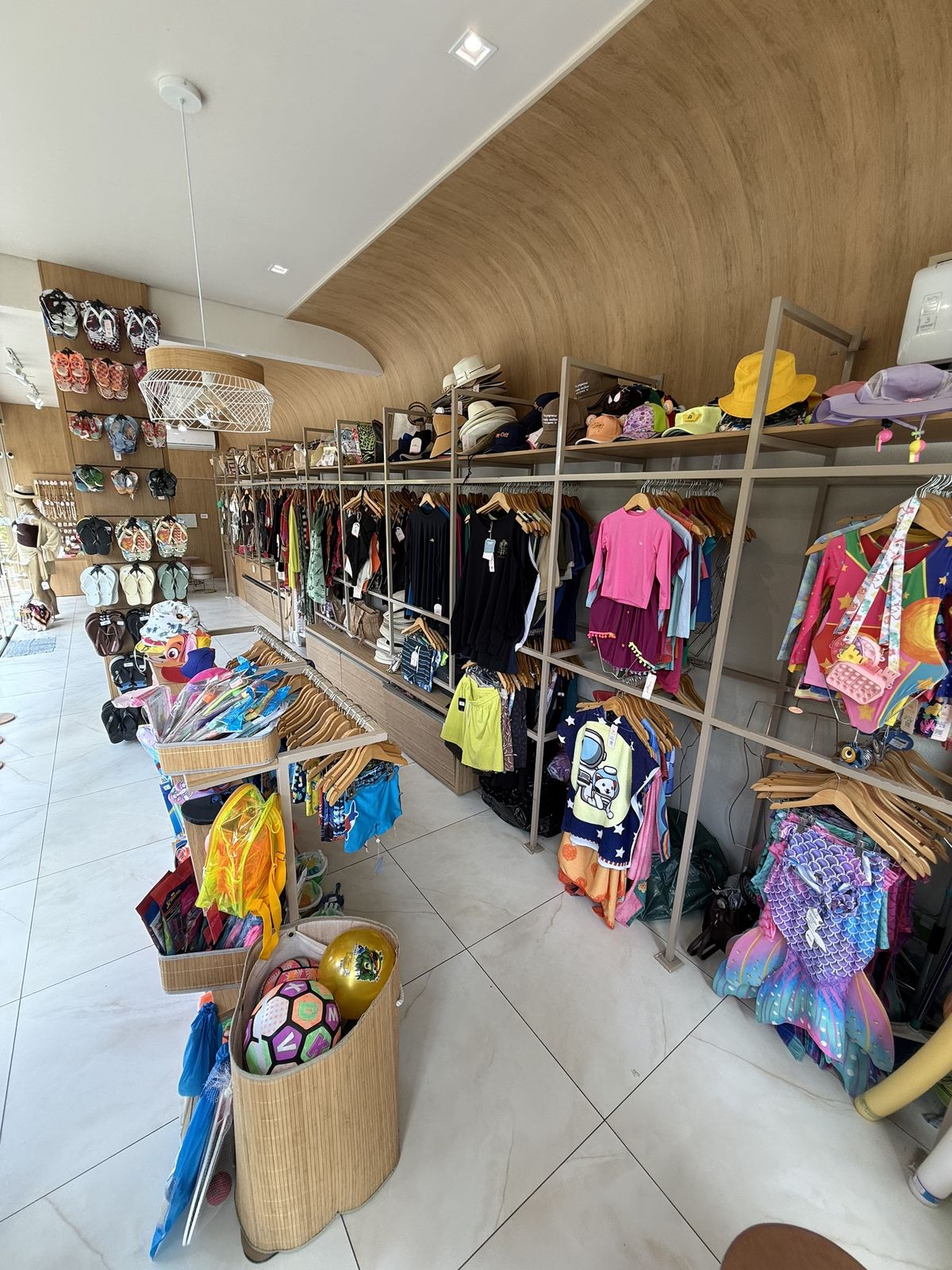 Araras de moda praia, chinelos e chapéus na loja